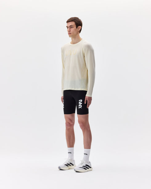 Person wearing a white long-sleeve shirt and black shorts with visible branding on a white background