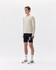 Person wearing a white long-sleeve shirt and black shorts with visible branding on a white background