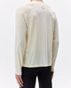 Person wearing a light-colored long-sleeve athletic shirt with a subtle pattern on a white background